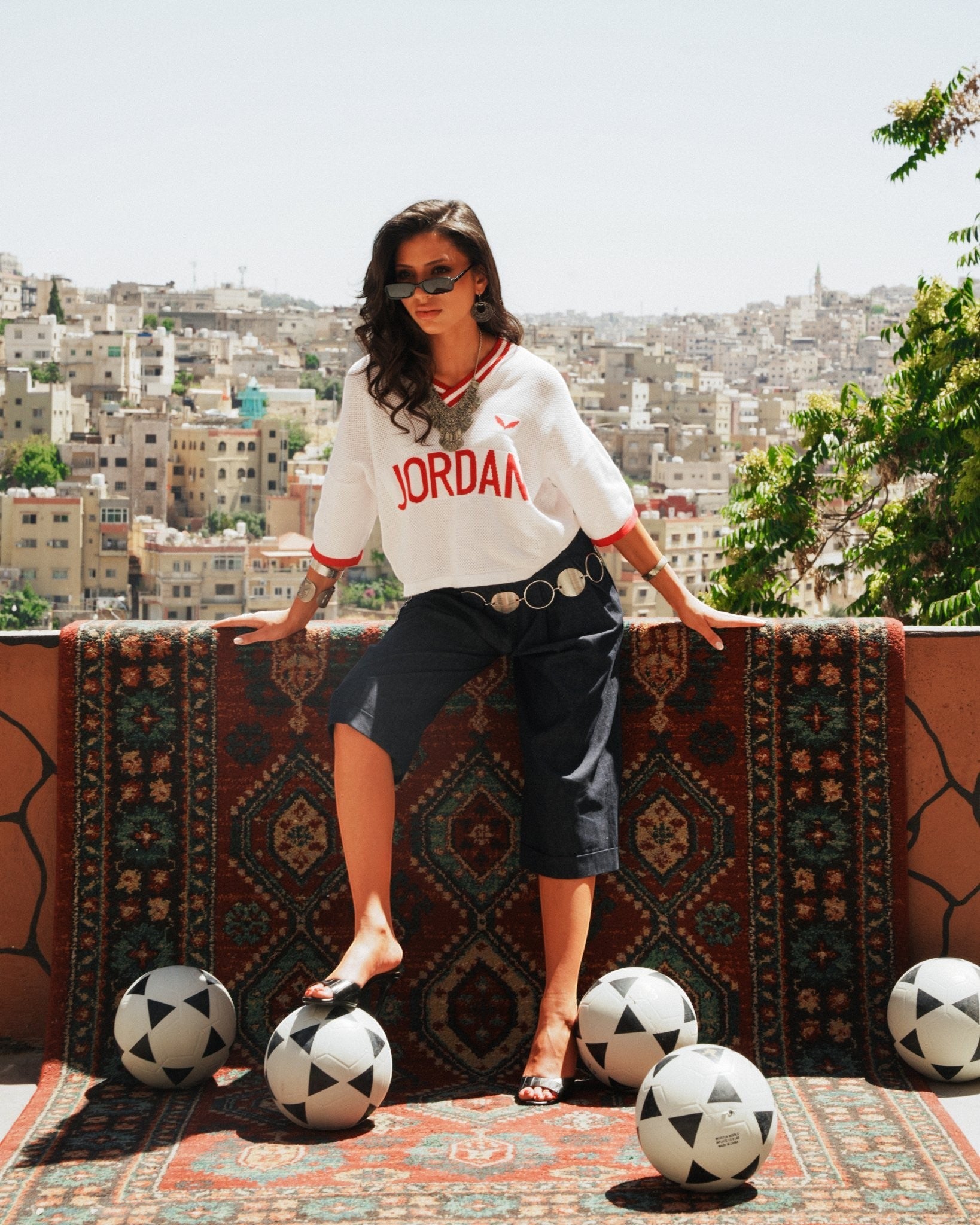 shorouqmazrawi indigo denim jorts with pleated front and cuffed hem worn by a model on a patterned rug in Amman