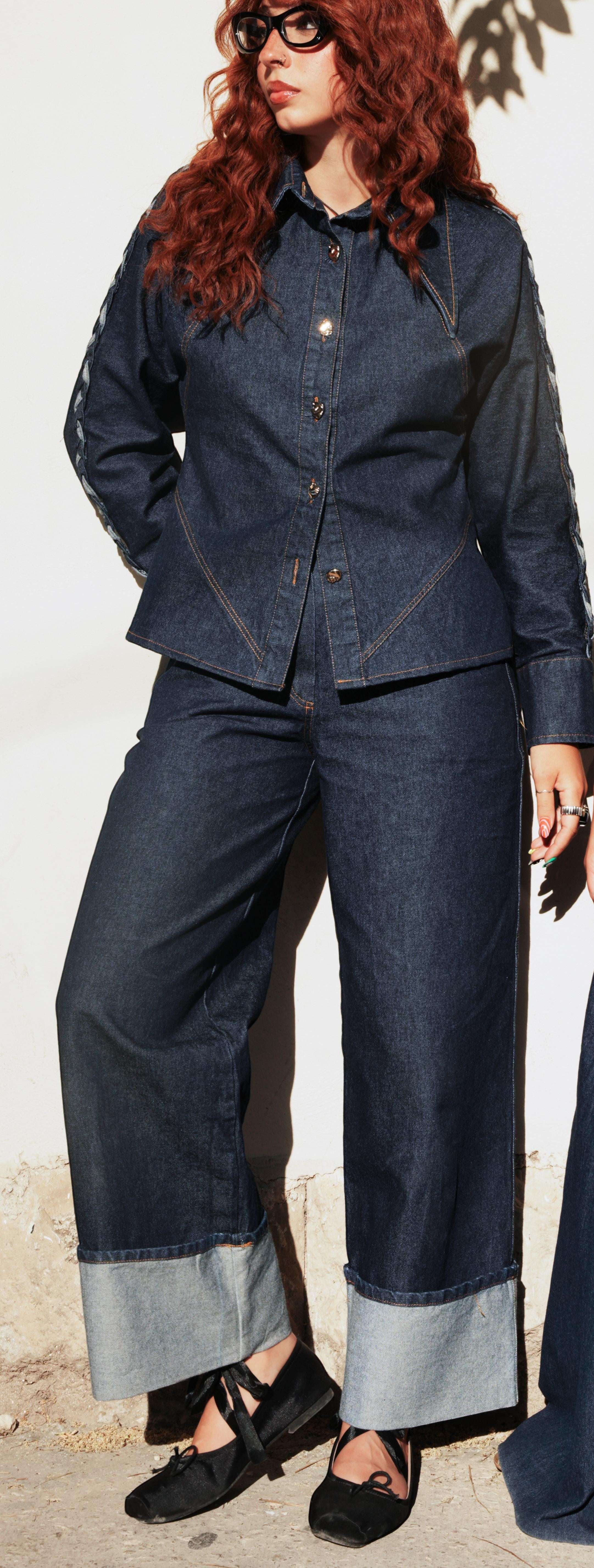 shorouqmazrawi indigo denim shirt with hand-braided shoulder trim and gold buttons worn with matching cuffed denim pants