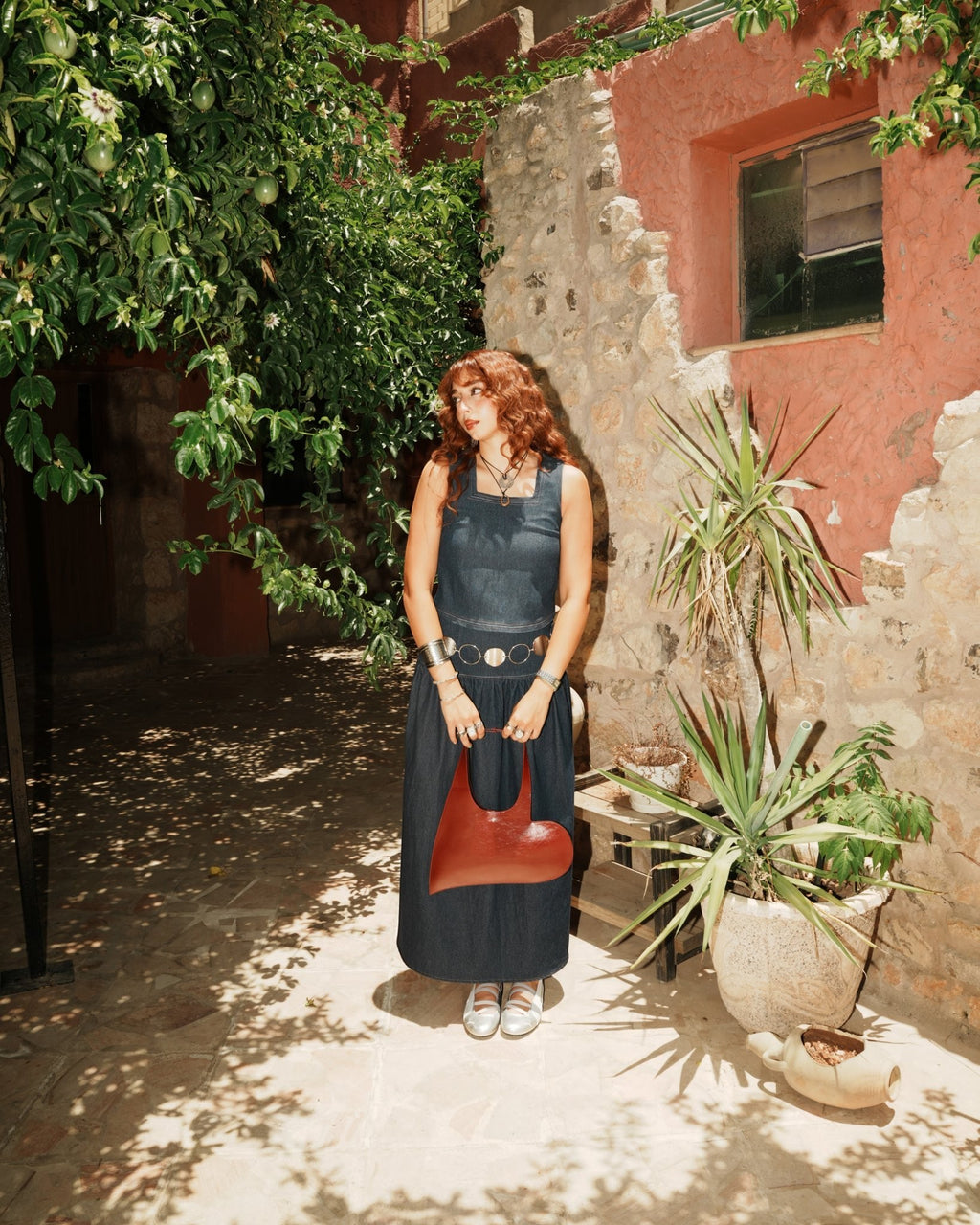 shorouqmazrawi indigo denim square-neck top with contrast stitching and side slits worn by a woman in a garden setting